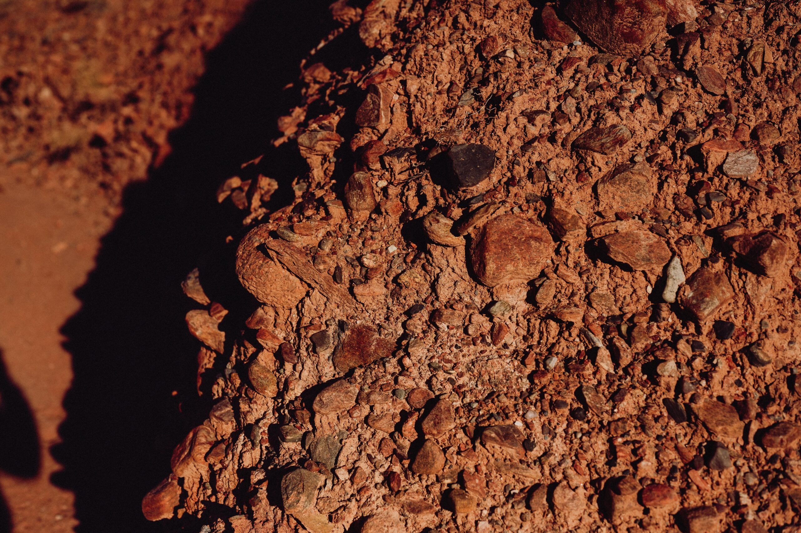 Detailed view of rugged red earth and pebbles, highlighting texture and natural patterns.